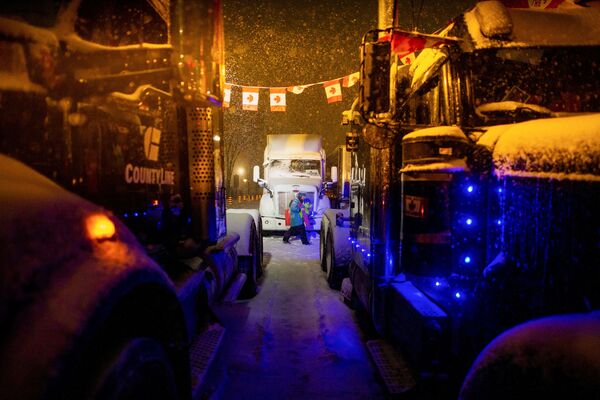 Zăpadă cade în timp ce camioanele sunt văzute parcate de-a lungul străzii Wellington, în timpul protestelor împotriva vaccinării obligatorii, de-a lungul străzii Wellington, lângă Parlamentul Canadei, în Ottawa, Ontario, Canada, 17 februarie 2022. - Sputnik Moldova-România