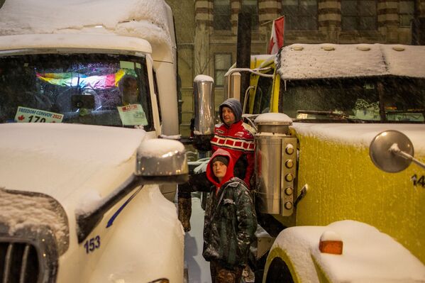 Oamenii discută între două camioane în timpul protestelor împotriva vaccinării obligatorii, de-a lungul străzii Wellington, lângă Parlamentul Canadei, în Ottawa, Ontario, Canada, 17 februarie 2022. - Sputnik Moldova-România