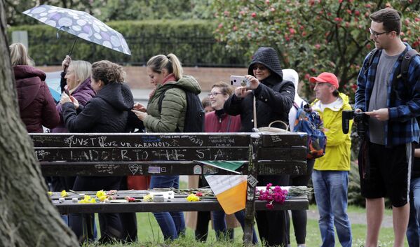 Толпа смотрит на скамейку в парке, покрытую посланиями, цветами и свечами в честь покойного Курта Кобейна, США. - Sputnik Молдова