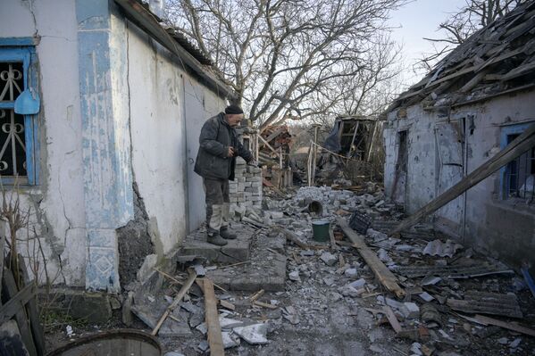 Localnic, Valeriu, în vârstă de 63 de ani, arată o clădire despre care a spus că a fost avariată de recentul bombardament în satul Taramciuk din regiunea Donețk, Ucraina, 20 februarie 2022 - Sputnik Moldova-România