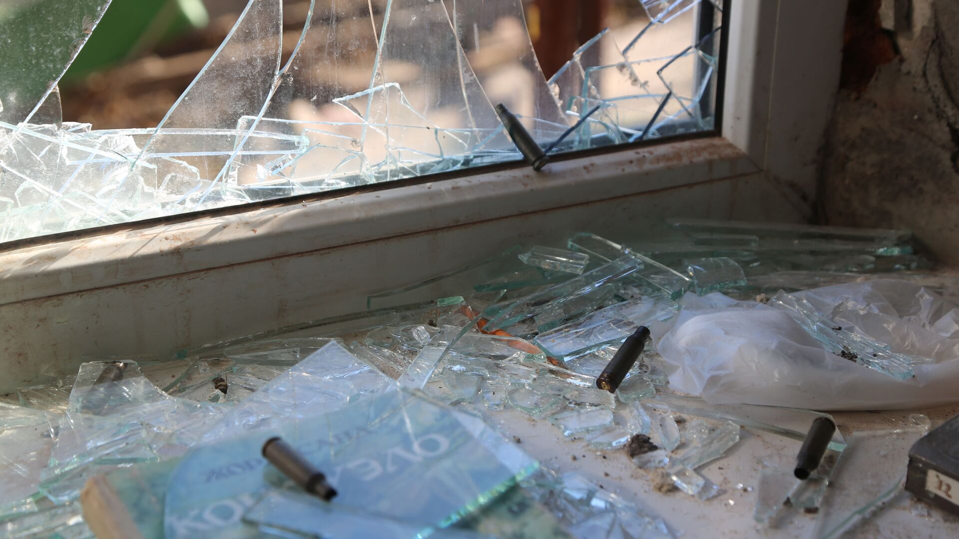 Разбитое окно и гильзы на подоконнике в жилом доме в Киевском районе Донецка - Sputnik Moldova-România, 1920, 13.03.2022