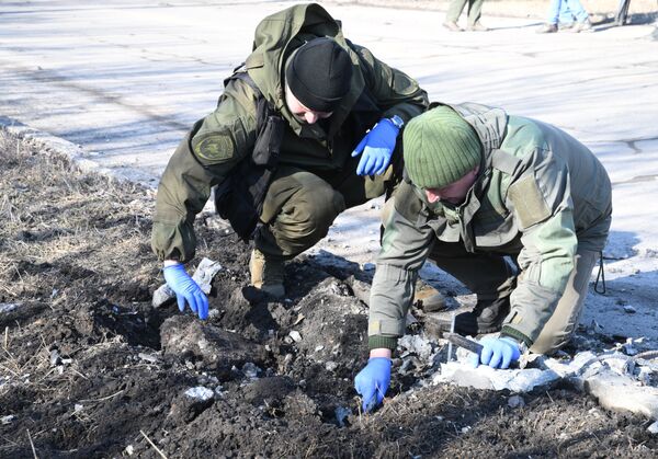 Сотрудники народной милиции ДНР осматривают место взрыва в Петровском районе Донецка после обстрела - Sputnik Молдова