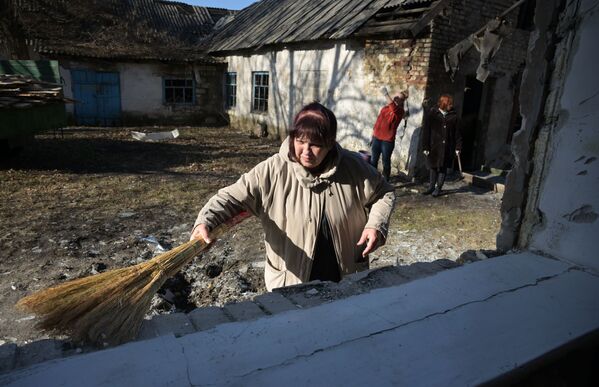 Женщина убирает осколки окон поврежденного в результате обстрела здания школы в Петровском районе Донецка - Sputnik Молдова