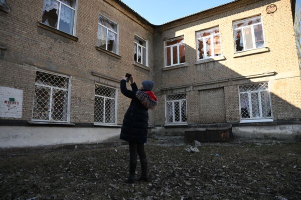 Женщина осматривает поврежденные в результате обстрела окна в здании школы в Донецке - Sputnik Молдова