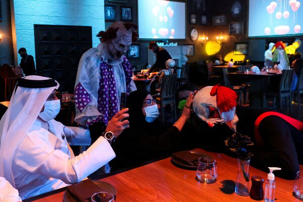 Женщина прикасается к голове клоуна во время обеда в тематическом ресторане ужасов Shadows в Эр-Рияде, Саудовская Аравия. - Sputnik Молдова