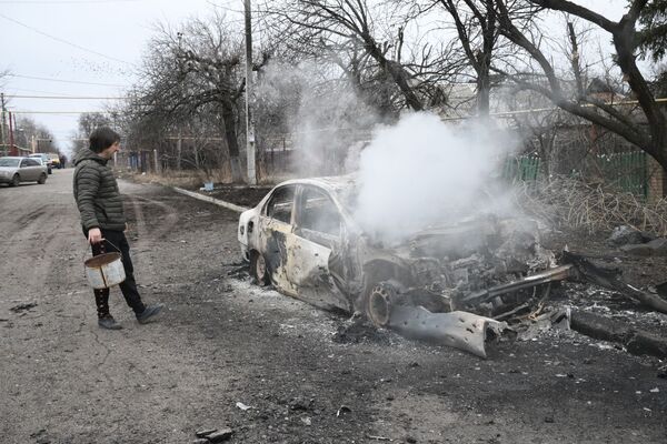 Un bărbat stă lângă o mașină arsă, în Donețk. - Sputnik Moldova-România