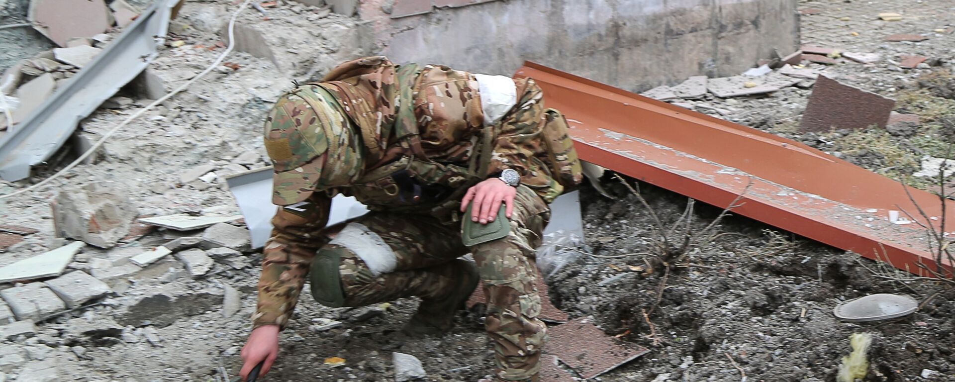 Военнослужащий обследует воронку от взрыва во дворе многоэтажного жилого дома в Донецке, поврежденного в результате обстрела - Sputnik Молдова, 1920, 19.09.2022