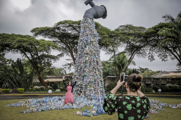 Люди фотографируются на фоне гигантской скульптуры, изображающей кран, из которого выливаются пластиковые бутылки. Найроби, Кения. - Sputnik Молдова