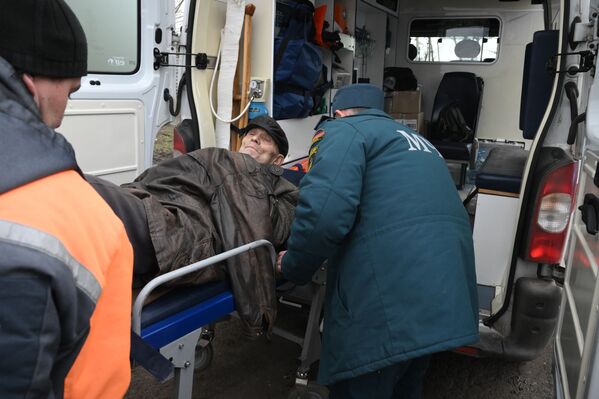 Сотрудники МЧС переносят пожилого человека, добравшегося из Мариуполя до пункта приема беженцев в санитарную машину. - Sputnik Молдова