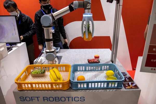 Сотрудник демонстрирует робота-сборщика, разработанного компанией Ascent Robotics, на Международной выставке роботов в Токио 9 марта 2022 года. - Sputnik Молдова