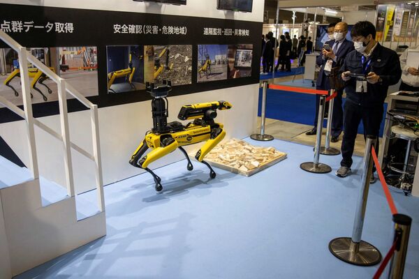 Сотрудник (справа) демонстрирует маневренного мобильного робота Spot® на Международной выставке роботов в Токио 9 марта 2022 г. - Sputnik Молдова