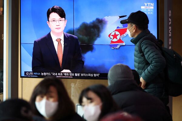 Люди в Южной Корее смотрят по телевизору репортаж о запуске Северной Кореей баллистической ракеты 5 марта 2022 года. - Sputnik Молдова