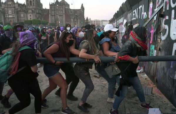 Femeile încearcă să spargă gardul care protejează Palatul Național, în timpul unei demonstrații de marcare a Zilei Internaționale a Femeii în Mexico City, pe 8 martie 2022. - Sputnik Moldova-România