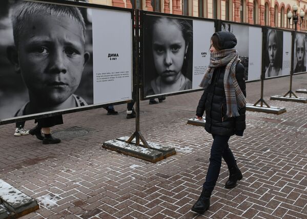 O fată de pe strada Arbat din Moscova, unde s-a deschis expoziția de fotografii „Priviți în ochii Donbas-ului”, cu fotografii cu copii din zona acțiunilor militare din Donbas. - Sputnik Moldova-România