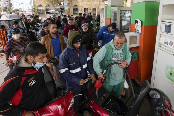 Șoferii de motociclete așteaptă să primească combustibil la o benzinărie din suburbiile din sudul orașului Beirut, Liban, 7 martie 2022. - Sputnik Moldova-România