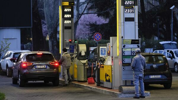 Работник меняет цены на топливо на табло на заправочной станции в Милане - Sputnik Молдова