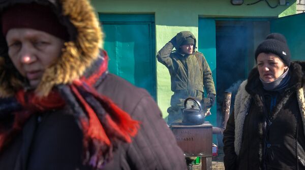 Locuitorii trec pe lângă un militar al Miliției Populare în orașul Volnovaha, care a intrat sub controlul Republicii Populare Donețk (RPD). - Sputnik Moldova