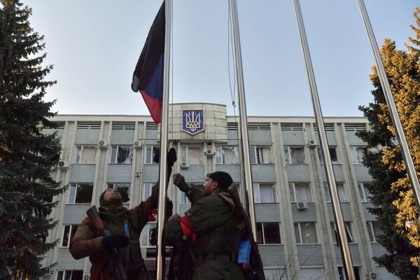 Luptătorii Miliției Populare din RPD ridică steagul de stat al Republicii Populare Donețk lângă clădirea administrației orașului din Volnovaha. - Sputnik Moldova