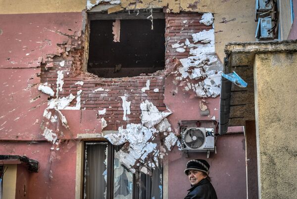 O femeie în vârstă trece pe lângă o casă avariată în urma bombardamentelor din orașul Volnovaha, care a intrat sub controlul Republicii Populare Donețk, RPD. - Sputnik Moldova