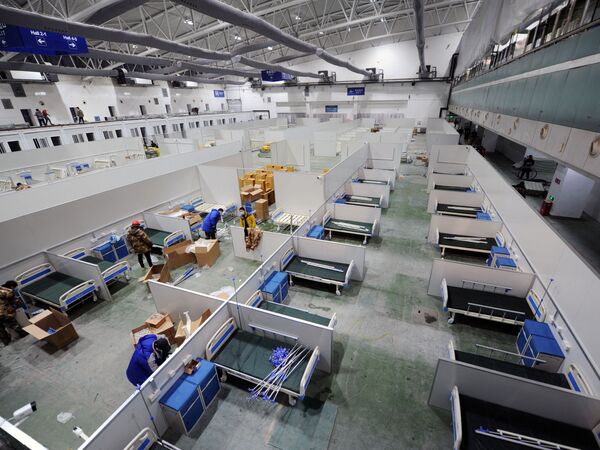 Рабочие устанавливают кровати на территории выставочного центра, который был превращен во временный госпиталь после вспышки коронавирусной инфекции в Чанчуне, провинция Цзилинь. - Sputnik Молдова
