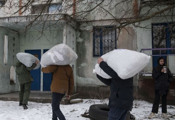 Loccalnicii îi ajută pe militarii Miliției Populare din RPL să descarce saci de ajutor umanitar în satul Teploe din Republica Populară Lugansk.  - Sputnik Moldova-România