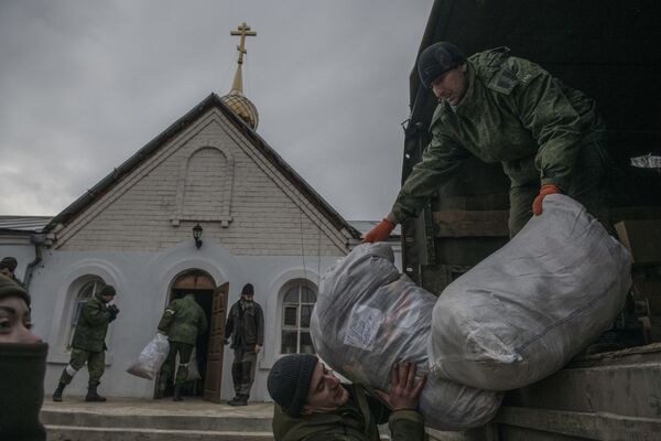 Militarii Miliției Populare din RPL descarcă saci de ajutor umanitar în satul Krasnîi Derkul, Republica Populară Lugansk.  - Sputnik Moldova-România