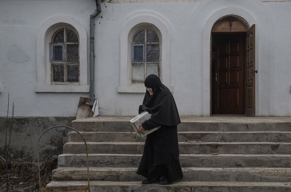 O călugăriță lângă Biserica Nașterea Maicii Domnului din satul Krasnîi Derkul. - Sputnik Moldova-România