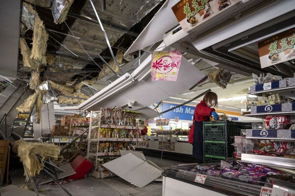 Сотрудник снимает товары с полок под поврежденным потолком в супермаркете в Сироиси, префектура Мияги, 17 марта 2022 года после землетрясения силой 7,3 балла, которое произошло накануне вечером на востоке Японии. - Sputnik Молдова