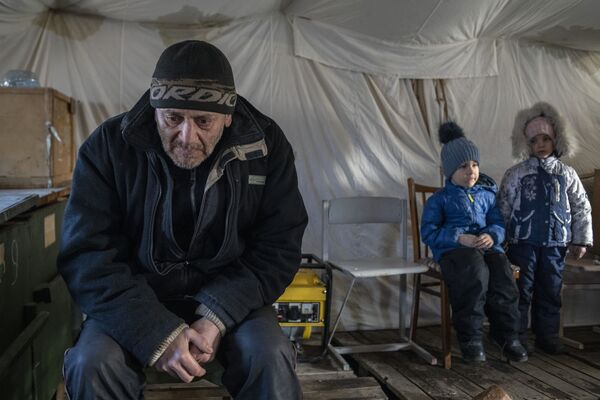 Un bărbat și copii în tabără de corturi din Starobilsk. Angajații Ministerului Situațiilor de Urgență din republica Populară Lugansk, împreună cu salvatorii acestui orașului Starobelsk, au înființat o tabără temporară de corturi pentru refugiați. - Sputnik Moldova