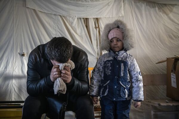 Un bărbat cu un copil în tabăra de corturi pentru refugiați din orașul Starobelsk. - Sputnik Moldova