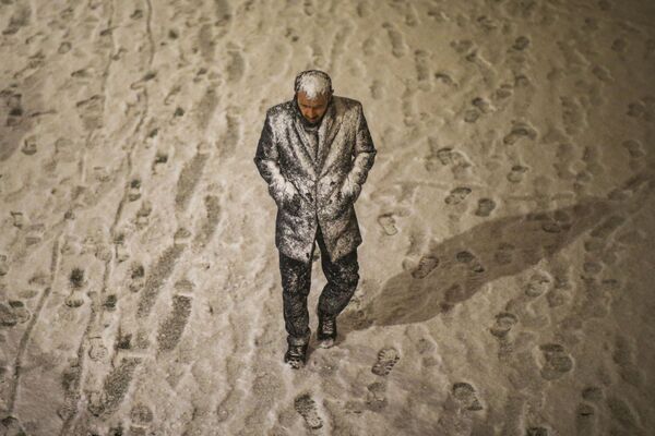 Un bărbat acoperit parțial de zăpadă se plimbă pe lângă podul Galata în timpul unei ninsori în Istanbul, Turcia, 12 martie 2022. - Sputnik Moldova-România