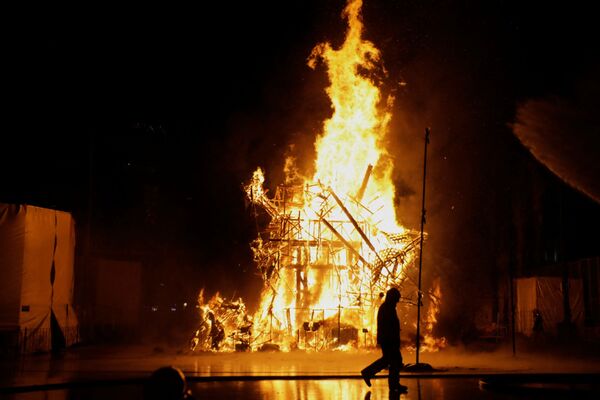 Пожарный напротив горящих деревянных фигур на празднике огня Фальяс в Валенсии. - Sputnik Молдова