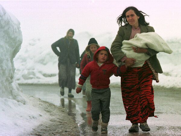 O mamă kosovară își conduce copiii care plâng din Pec, Kosovo, Iugoslavia, de-a lungul unui drum înzăpezit care duce la provincia iugoslavă din apropiere, Muntenegru, miercuri, 31 martie 1999. Mii de refugiați continuă să inunde din provincie. - Sputnik Moldova-România