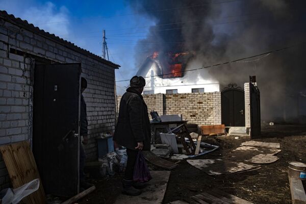 Жители села Варваровка Луганской области смотрят на горящий дом.  - Sputnik Молдова