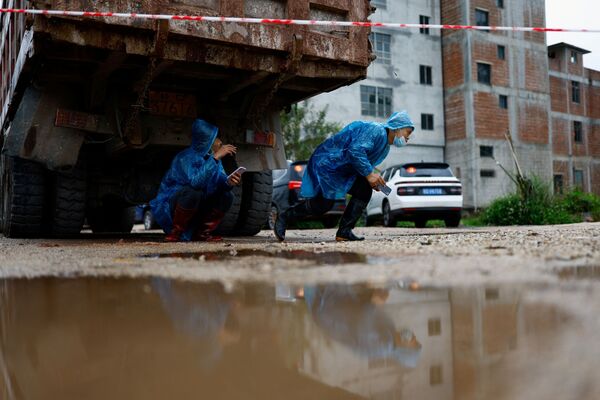 Люди прячутся от дождя под грузовиком недалеко от места крушения самолета Boeing 737-800 China Eastern Airlines в Китае. - Sputnik Молдова
