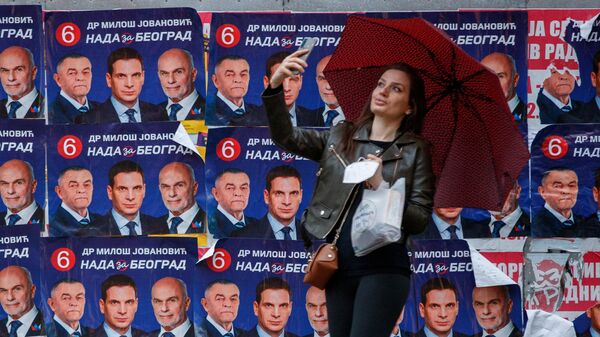 O fată își face un selfie lângă afișe electorale care îi înfățișează pe candidați sârbi la președinție, în Belgrad - Sputnik Moldova-România