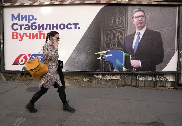 O femeie trece pe lângă un pano publicitar pre-electoral care îi arată pe actualul președinte sârb și lider al Partidului Progresist Sârb Aleksandar Vucic la Belgrad, Serbia, luni, 28 martie 2022. - Sputnik Moldova-România