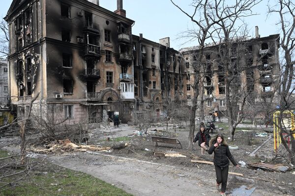 Жители города во дворе разрушенного жилого дома в Мариуполе - Sputnik Молдова