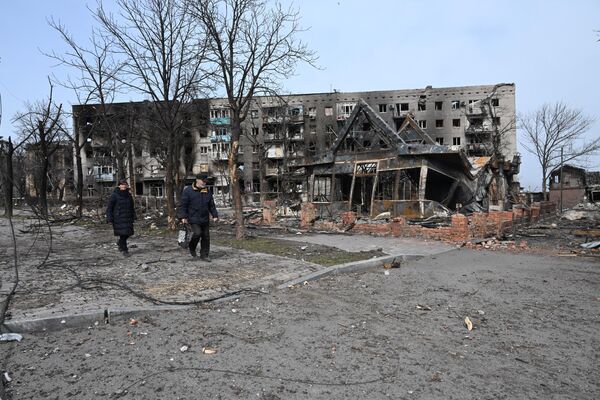 Жители города проходят мимо разрушенных жилых домов в Мариуполе - Sputnik Молдова