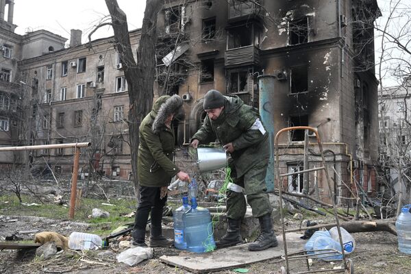 Боец Народной милиции ДНР помогает жительнице города набрать воды у колодца в Мариуполе. - Sputnik Молдова