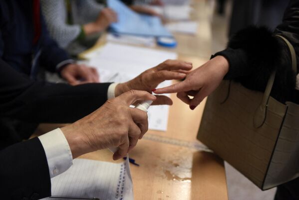 Un funcționar electoral folosește un spray pentru a marca o persoană care a votat deja, în timpul alegerilor generale din țară, la o secție de votare din Belgrad, Serbia, 3 aprilie 2022. - Sputnik Moldova-România