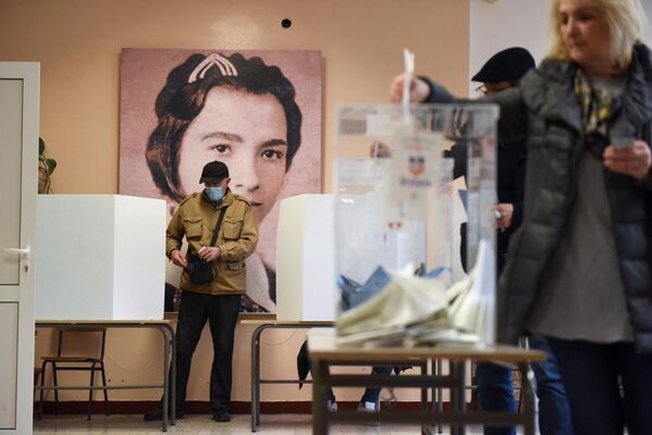 Un alegător care poartă o mască facială se pregătește să voteze, în timpul alegerilor generale din țară, la o secție de votare din Belgrad, Serbia, 3 aprilie 2022. - Sputnik Moldova-România