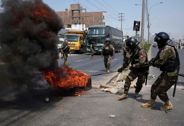 Poliția scoate anvelopele arse de pe Autostrada Centrală, unde camioane și autobuze sunt parcate pentru a bloca drumul în Huaycan, la periferia orașului Lima, Peru, luni, 4 aprilie 2022.   - Sputnik Moldova
