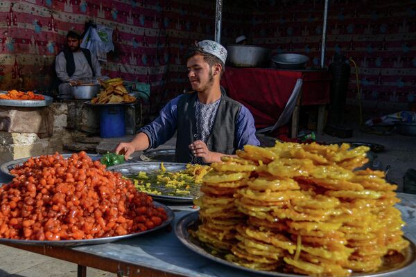 Продавец сладостей ждет покупателей в первый день священного месяца поста Рамадан в Кандагаре. - Sputnik Молдова