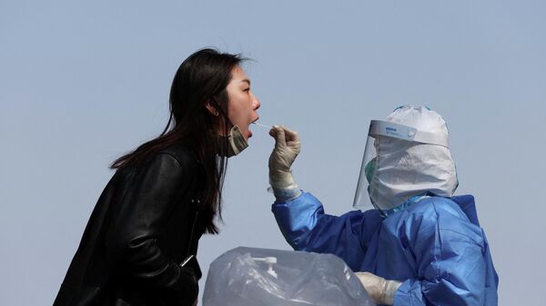 Медицинский работник в защитном костюме берет образец мазка у человека на участке тестирования в Пекине - Sputnik Молдова