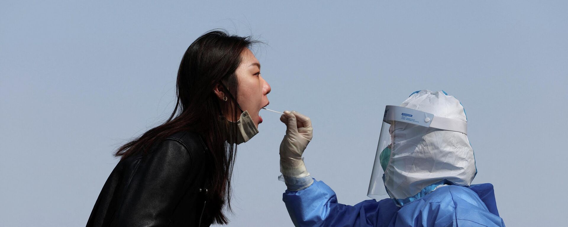 Медицинский работник в защитном костюме берет образец мазка у человека на участке тестирования в Пекине - Sputnik Молдова, 1920, 06.04.2022
