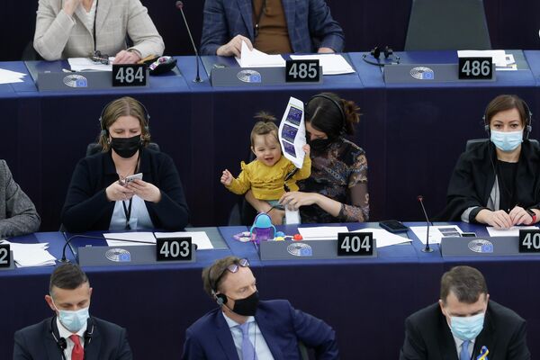 Ирена Йовева из Словении (в центре) держит ребенка на коленях, пока члены парламента принимают участие в дебатах по усилению применения принципа оплаты за равный труд мужчин и женщин в Европейском парламенте  в Страсбурге. - Sputnik Молдова