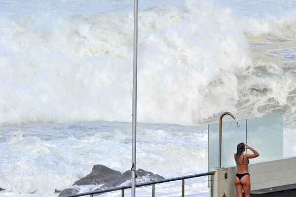 Женщина принимает душ после купания на пляже Бонди в Сиднее на фоне предупреждений об опасности. - Sputnik Молдова