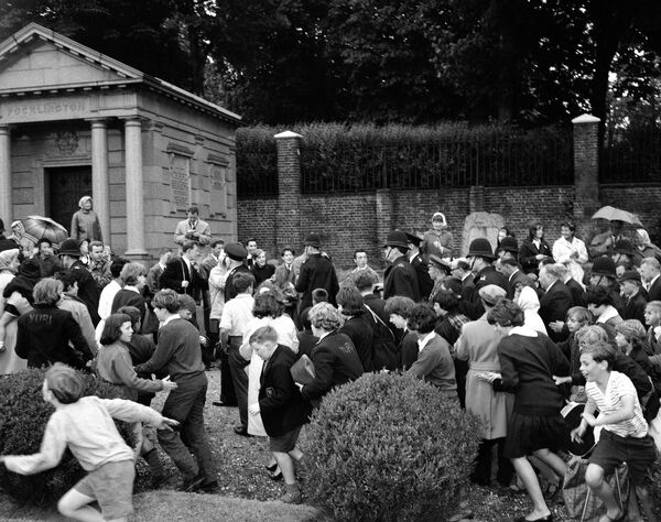 Maiorul Iuri Gagarin, astronaut rus (în dreapta centrului), este escortat prin cimitirul Highgate din Londra, Regatul Unit, la 14 iulie 1961, când a depus o coroană de flori la mormântul lui Karl Marx, venerat ca unul dintre autorii comunismului. Copiii fug prin cimitir pentru a-l vedea pe eroul spațiului prezent la ceremonie. - Sputnik Moldova-România