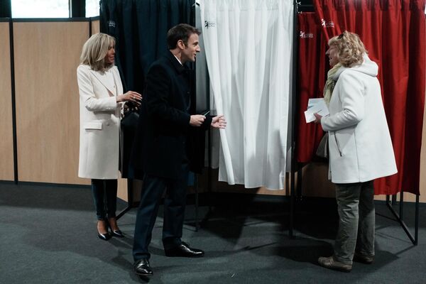 Președintele Franței și candidatul la președinția partidului LREM Emmanuel Macron, alături de soția sa Brigitte Macron, vorbește cu un rezident înainte de a vota pentru primul tur al alegerilor prezidențiale din Franța la o secție de votare din Le Touquet, nordul Franței, pe 10 aprilie, 2022. - Sputnik Moldova